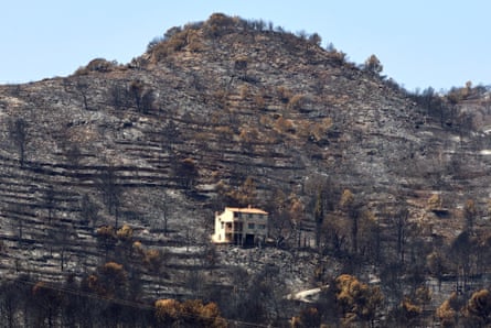 A house sits on the scorched slope of a tall hill