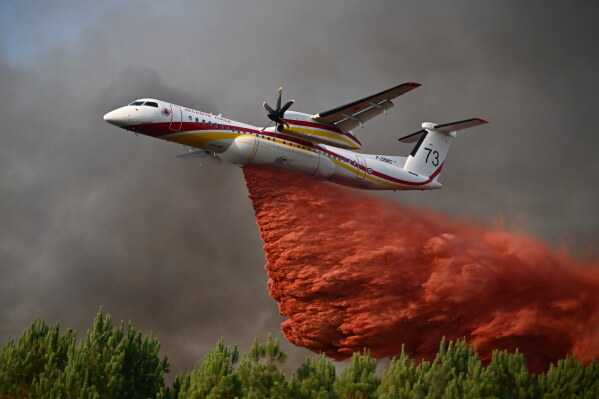 A plane releases fire retardant as it flies over a forest near Blagon, during wildfires in southwestern France, July 29, 2026. (AP Photo/Emma Da Silva, File)