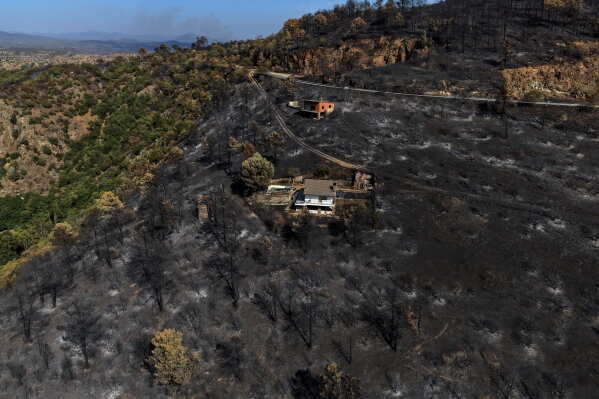 An area scorched by a wildfire surrounds structures in El Tiemblo, Avila province, Spain, Thursday, July 30, 2026. (AP Photo/Manu Fernandez, File)