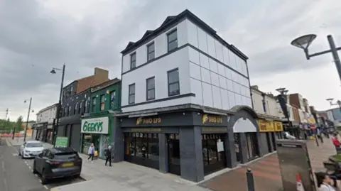Google 15 Waterloo Place. A Vietnamese pho restaurant is on the ground floor. The upper two storeys are white decorated with white cladding.