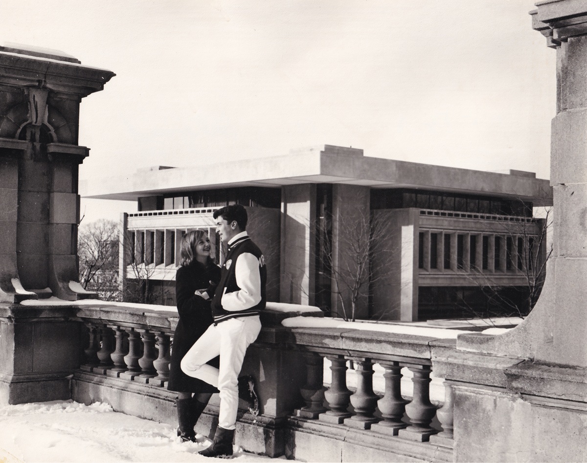 two people standing in front of railing with Newhouse building behind them