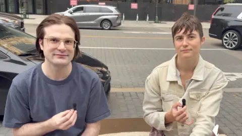 Two people hold microphones and give an interview