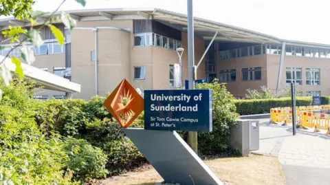 Getty Images The exterior of a large university building with a blue and orange sign outside reading 'University of Sunderland - Sir Tom Cowie Campus at St. Peter's.